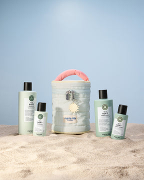 Set of Maria Nila hair care products and Beauty Bag on a sandy surface with a light blue background